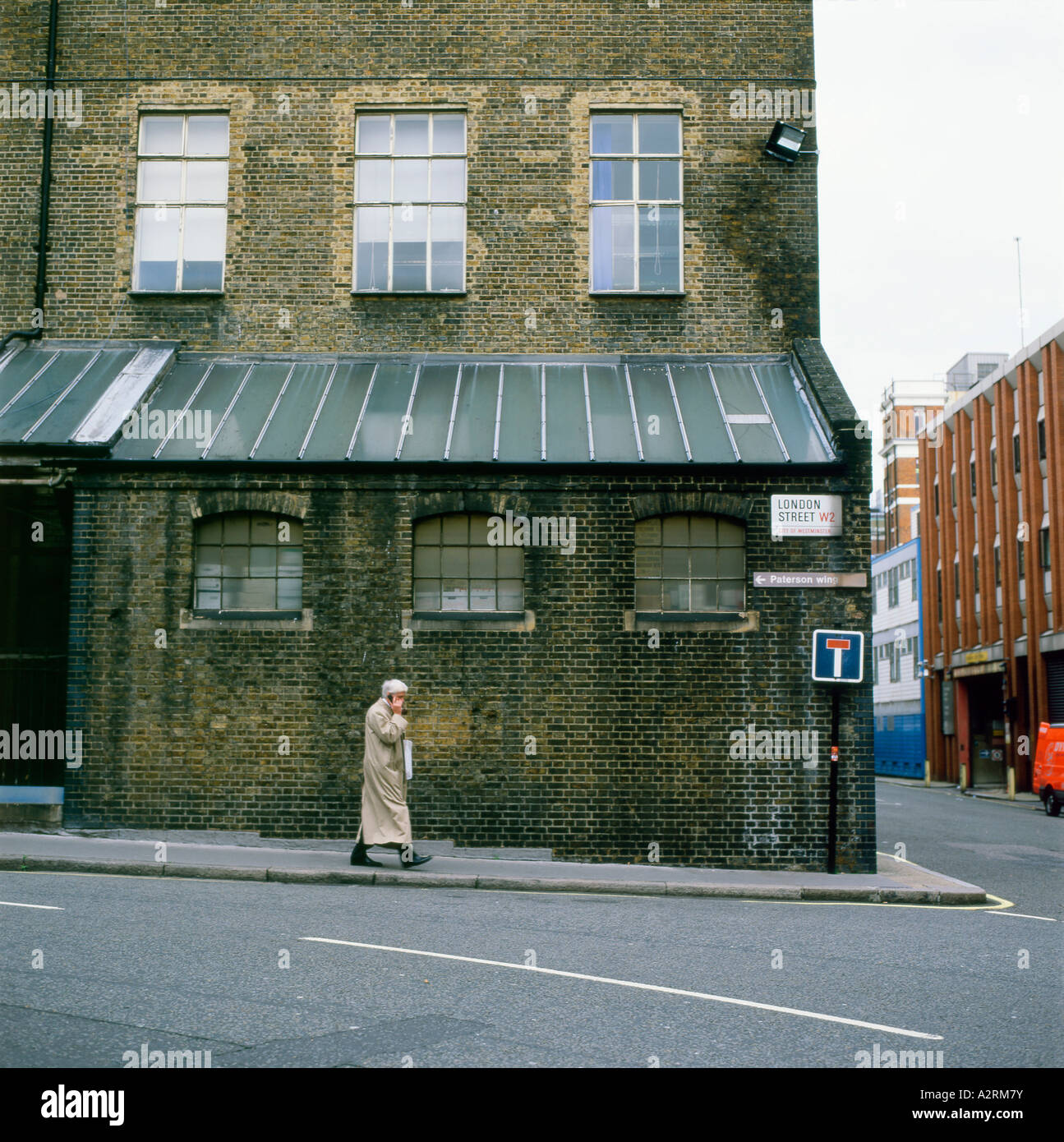A man wearing a mac talking on a mobile phone walking along London Street, Paddington London, England  UK    KATHY DEWITT Stock Photo