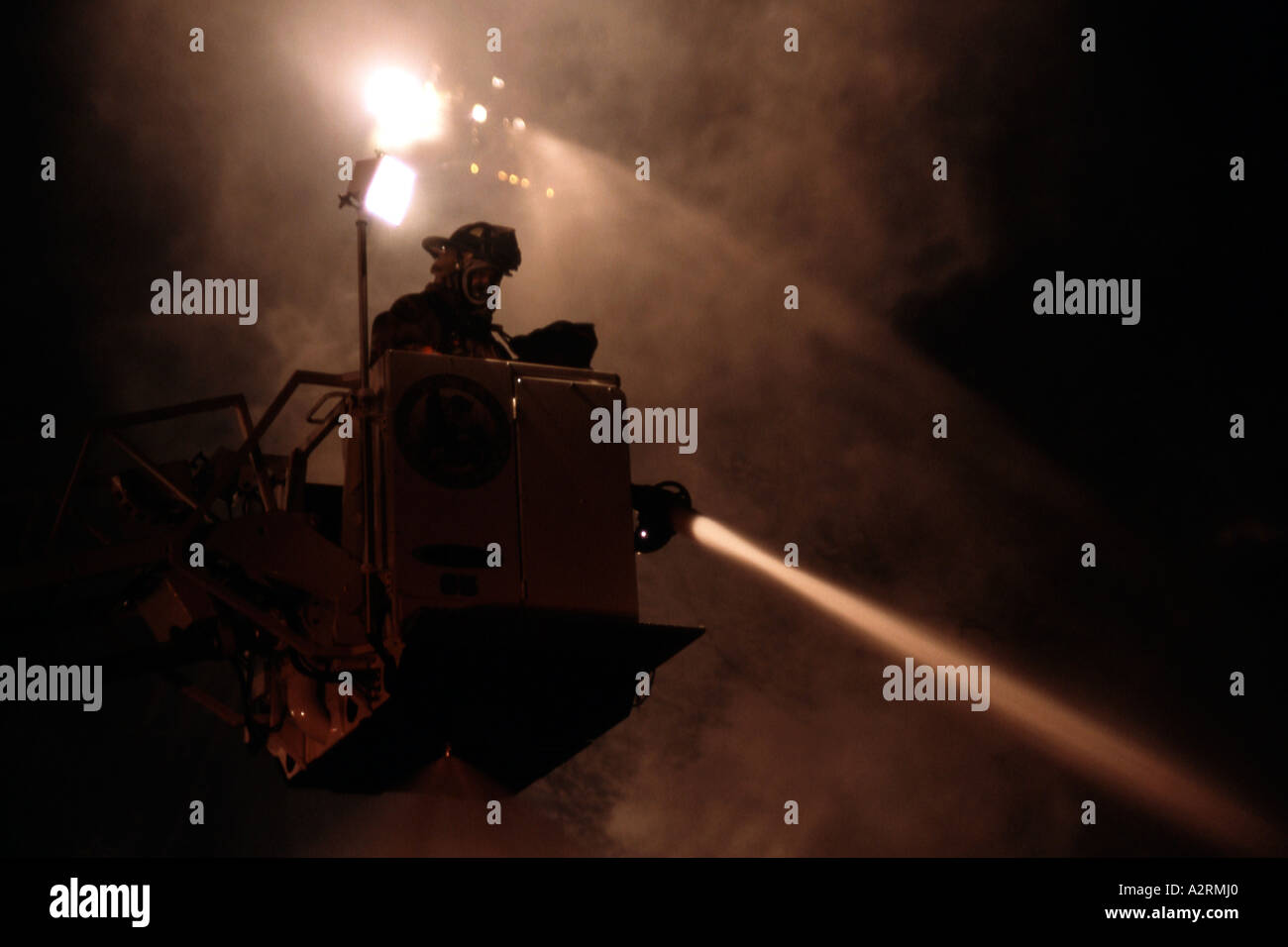 Fire fighters on a ladder platform pouring water onto a fire Stock