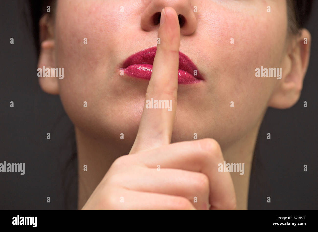 Young Woman Holding Index Finger to Lips Close Up Stock Photo