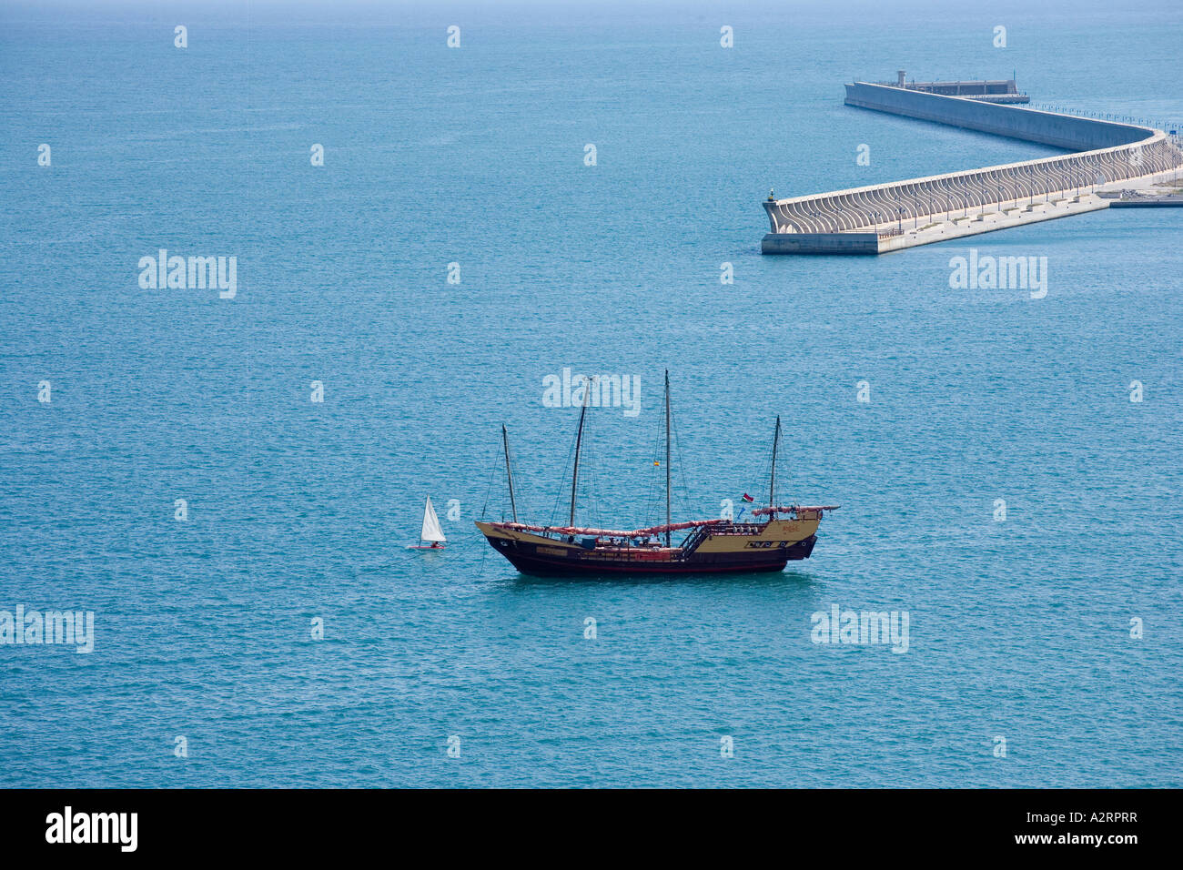 old ship of 4 masts and little sailboat in the sea near a port Stock Photo