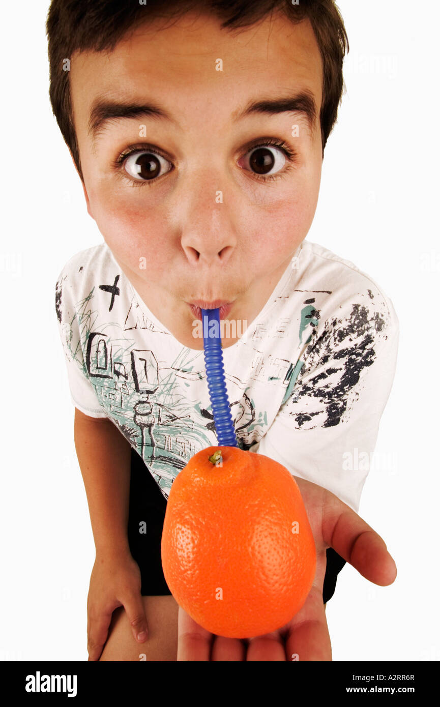 Child 10 years drinking juice from an orange with straw Model released Studio shot Stock Photo