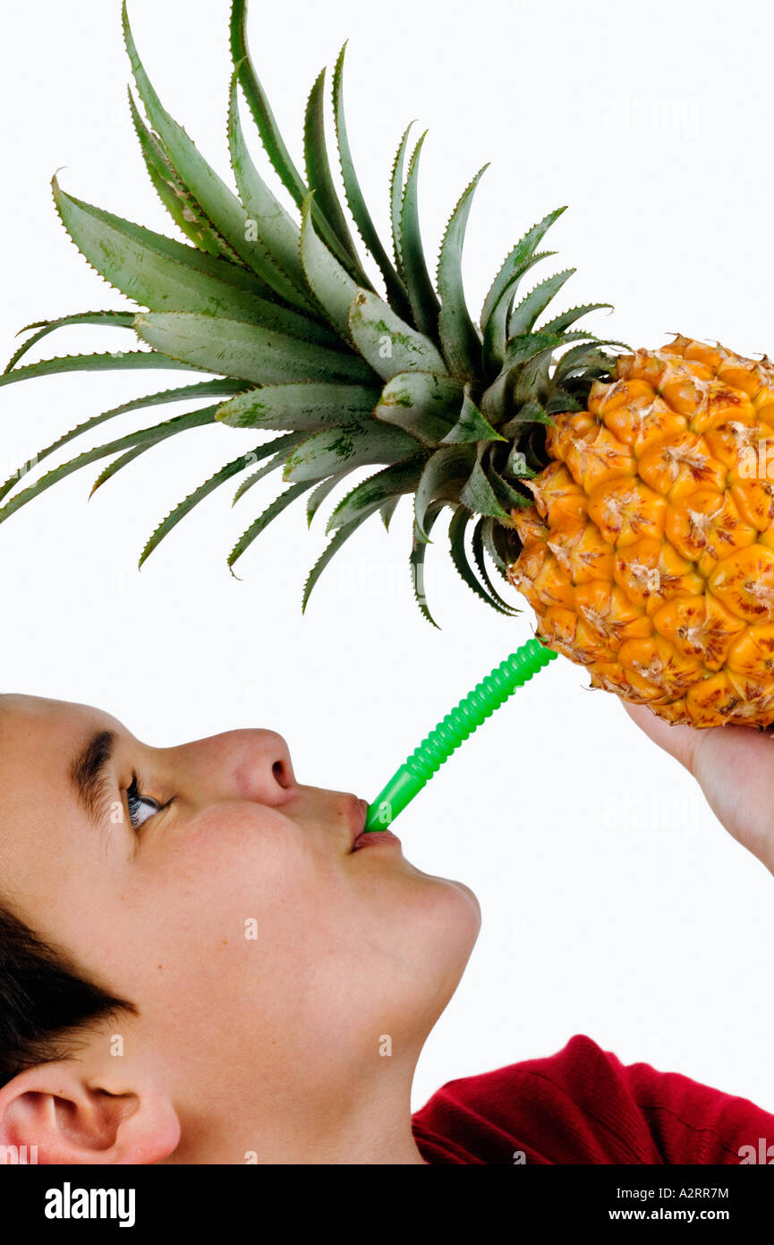 Child 10 years drinking juice from a pineapple with straw Model released Studio shot Stock Photo