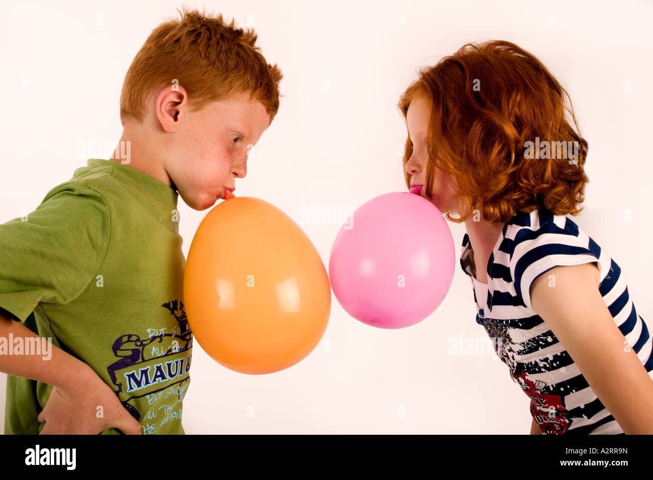 Red haired and freckled twins age7 Blowing up balloons Studio shot