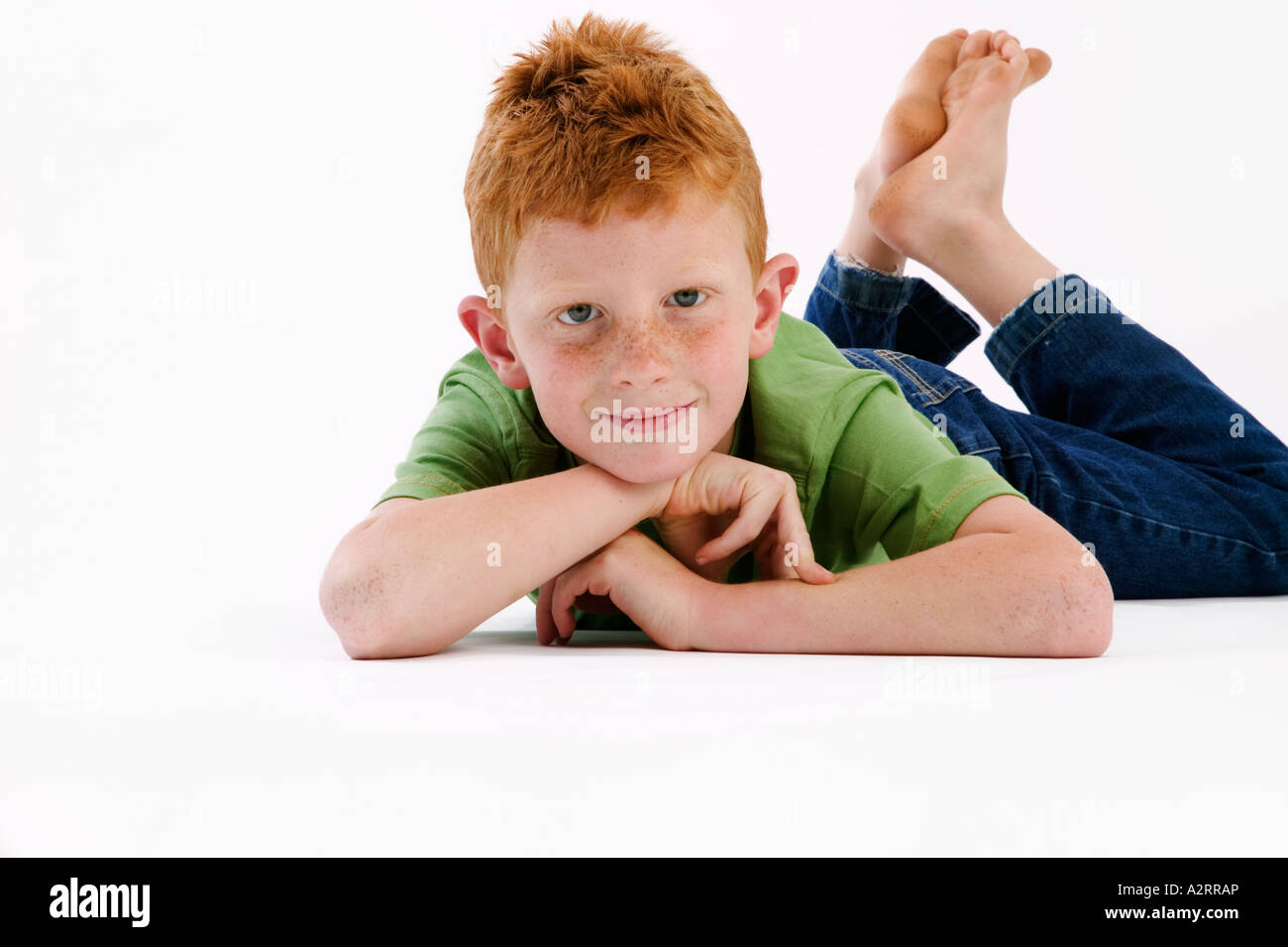 Young boy with red hair and freckles age 7 laying with his feet up Model Released Studio shot Stock Photo