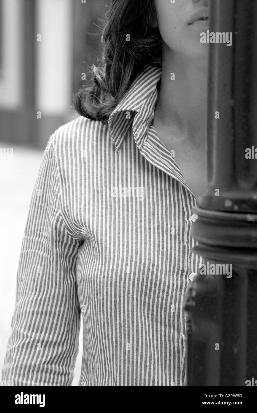 Black and white C.U. of young woman with striped shirt, half hidden behind a lamppost Stock Photo