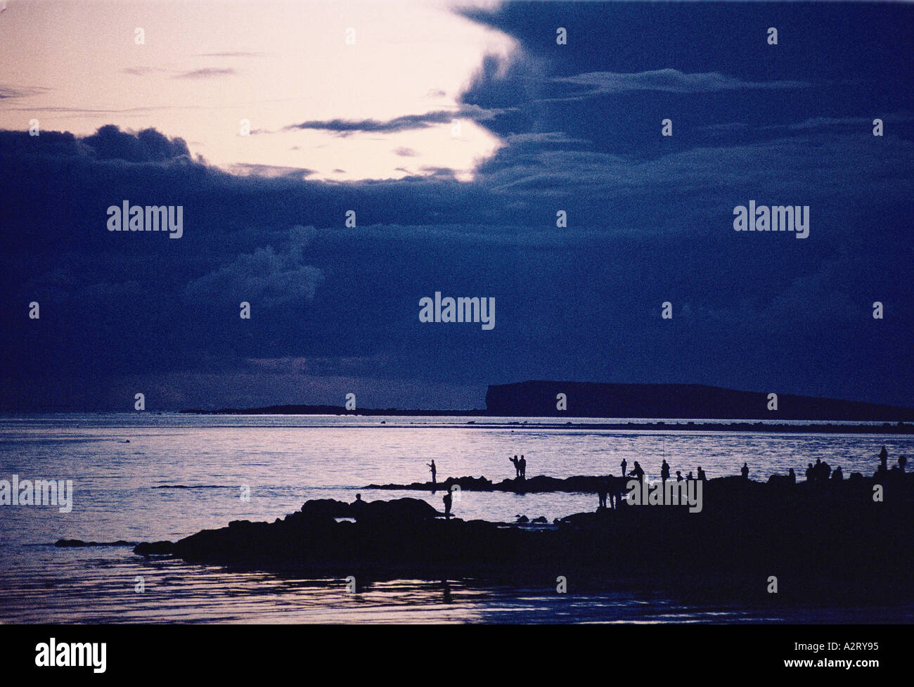 people fishing from rocky shoreline in lake at salthill galway eire
