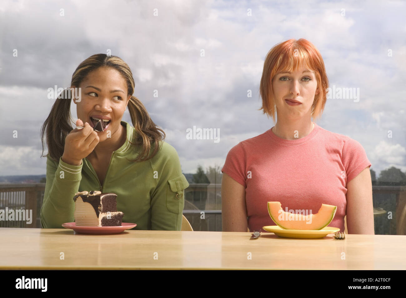Two women eating different food Stock Photo