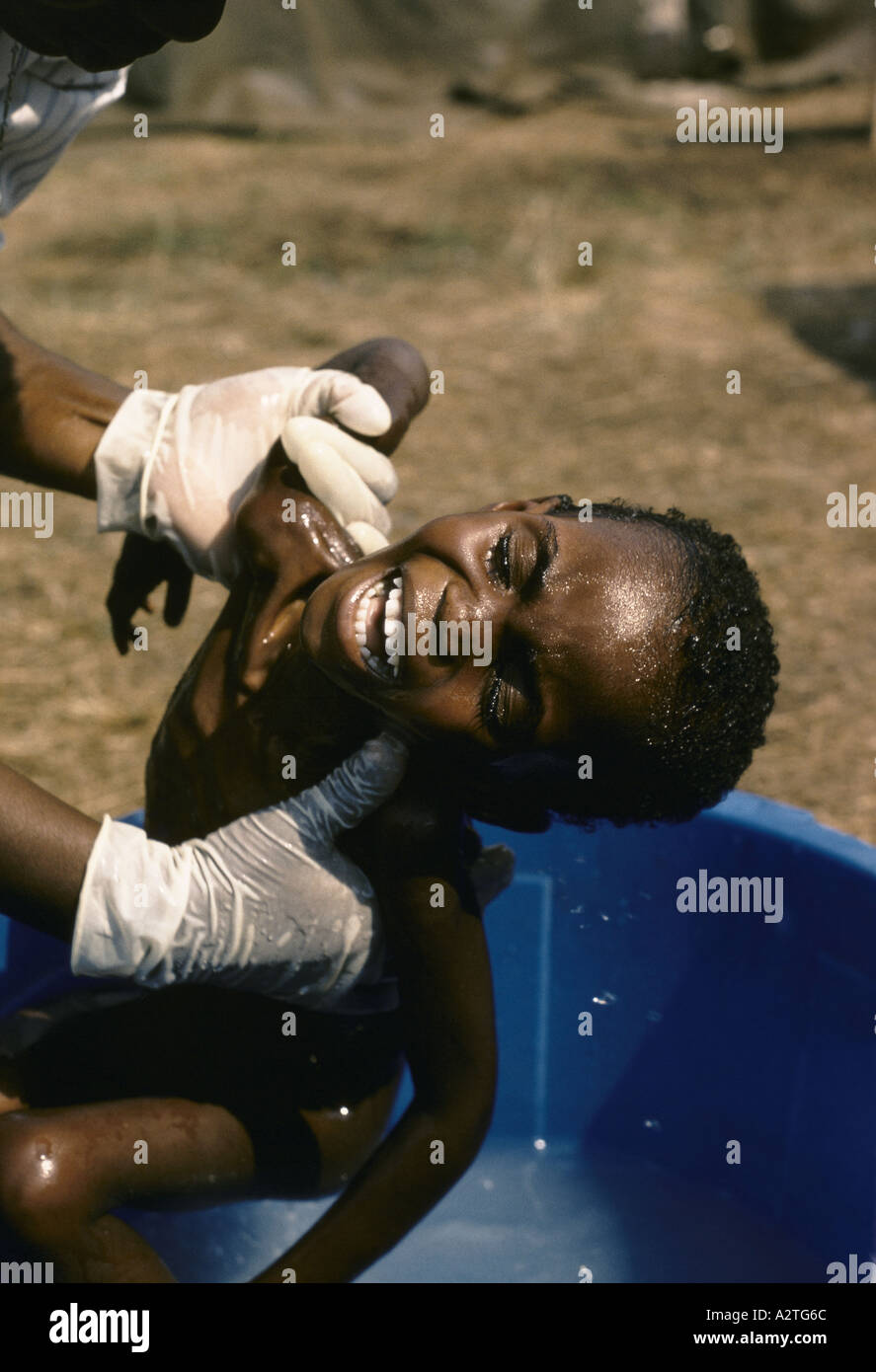 a rwandan child is lifted from bathtub crying in ndosho orphanage Stock Photo