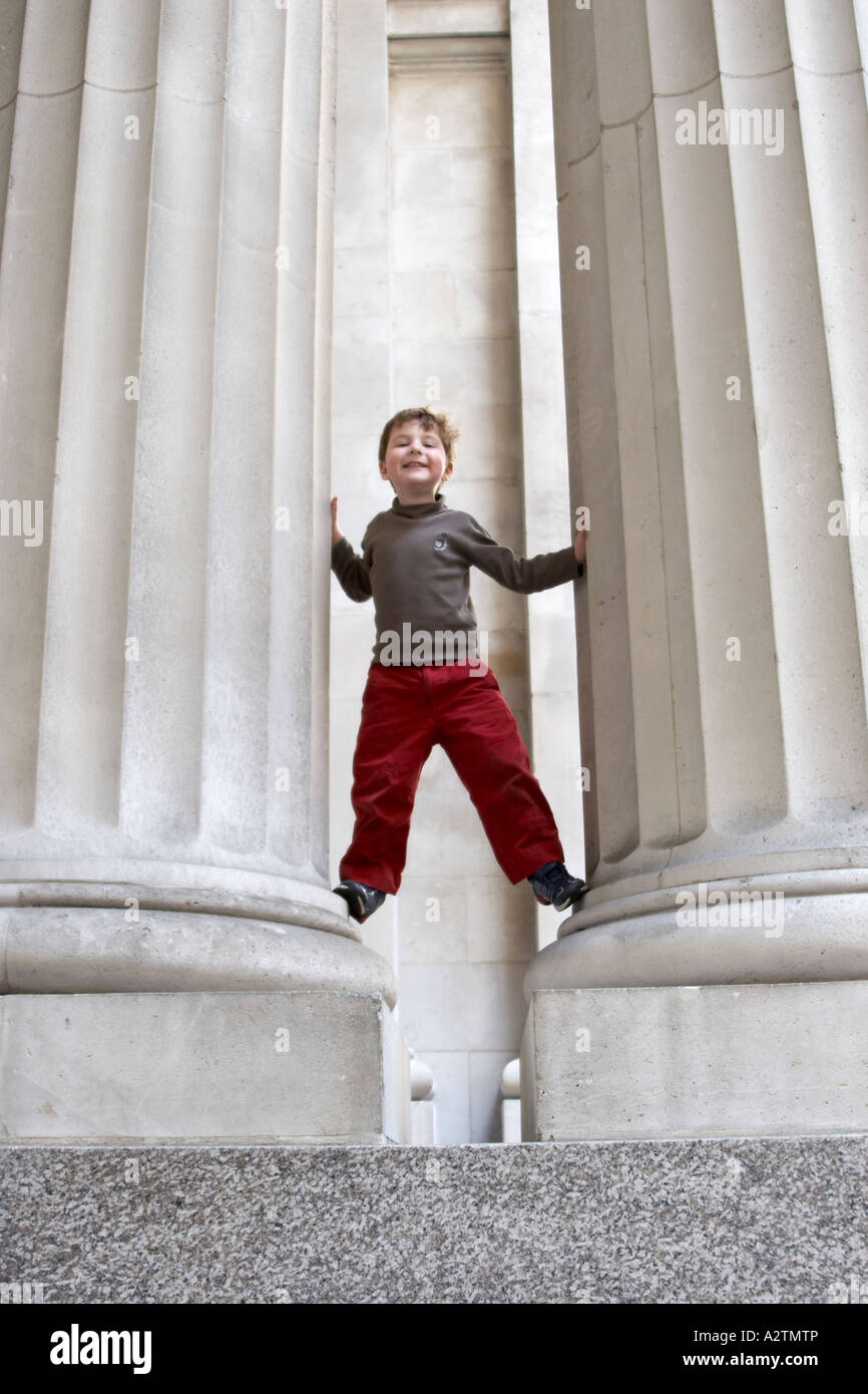 Young boy child on a standing between two pillars of S Helen s place City of London EC3 England UK NAOH Stock Photo