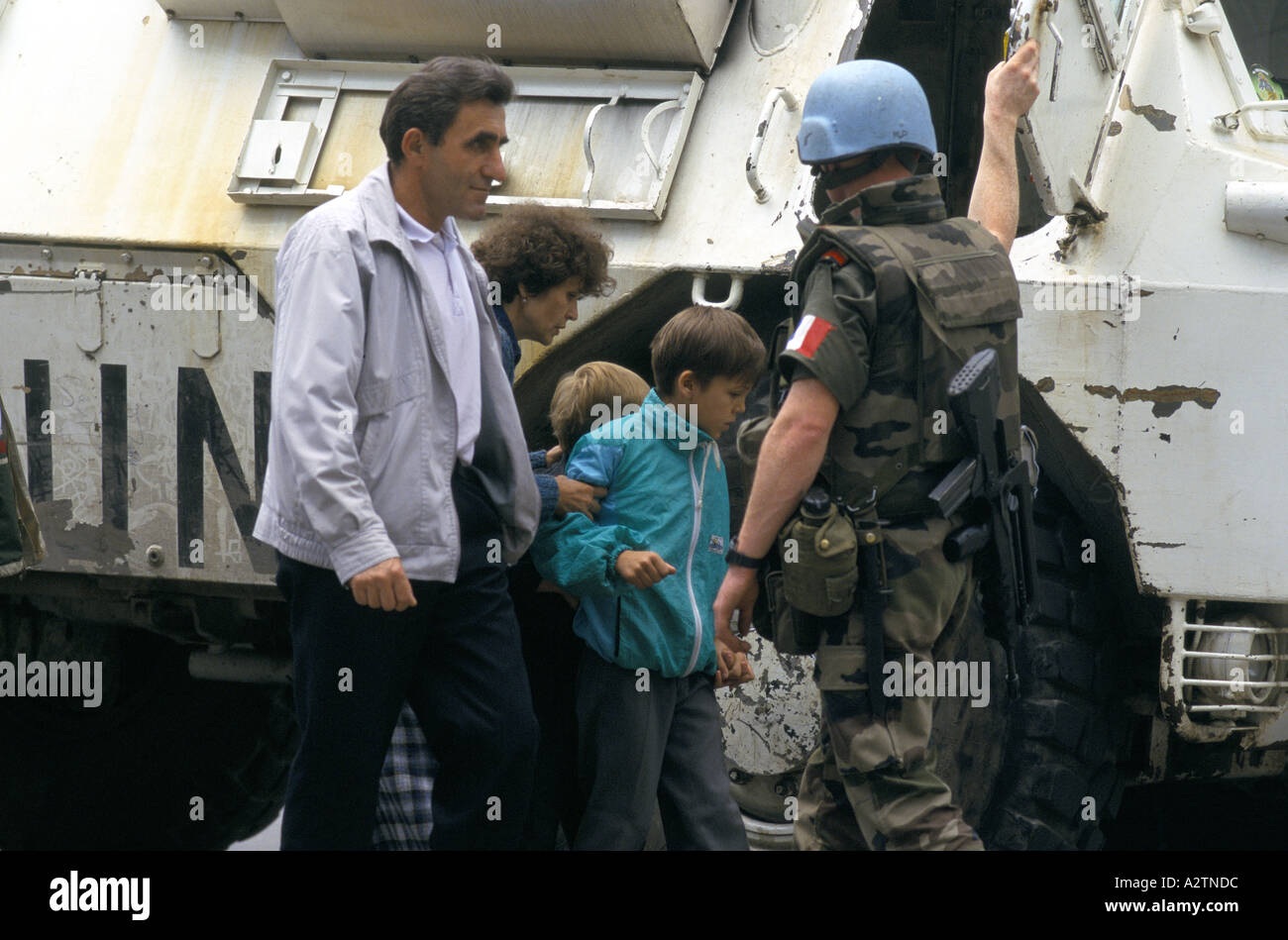 sarajevo june 1995 un tanks armed soldier shielding people with children as they cross sniper susceptible roads Stock Photo