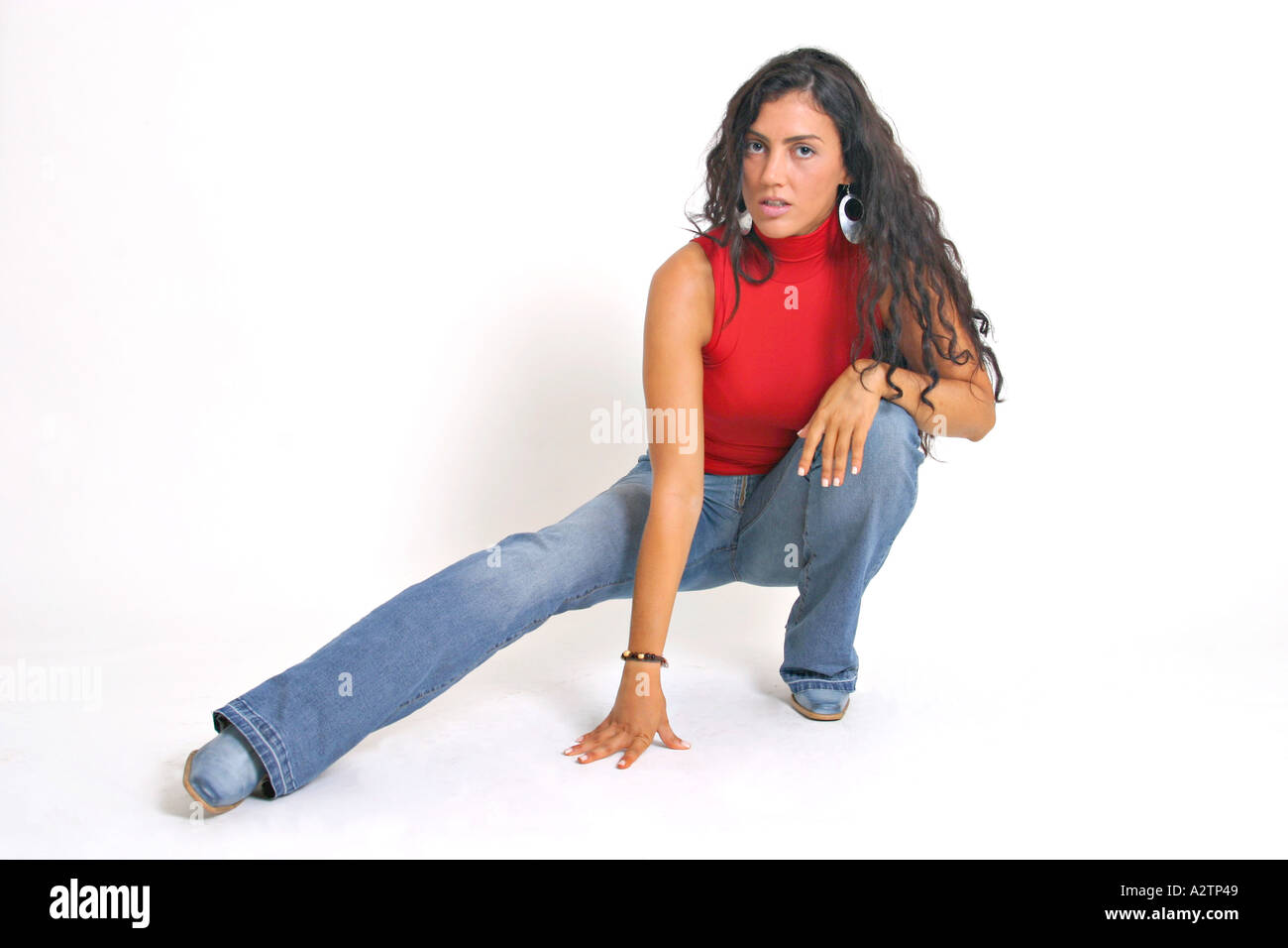 Full shot of Spanish girl with red top and jeans squatting with extended  leg Stock Photo - Alamy
