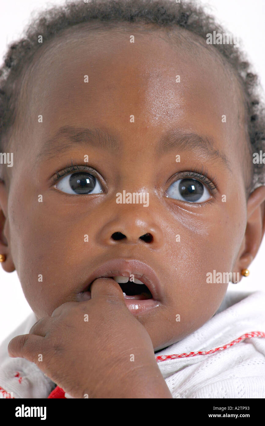 Black baby girl with her index finger in her mouth looking upwards