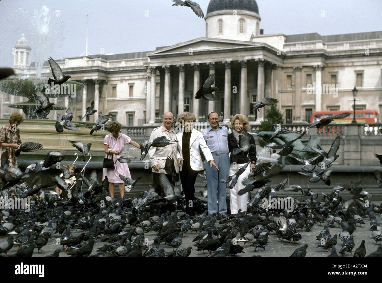 tourists in trafalgar square surrounded by pigeons Stock Photo