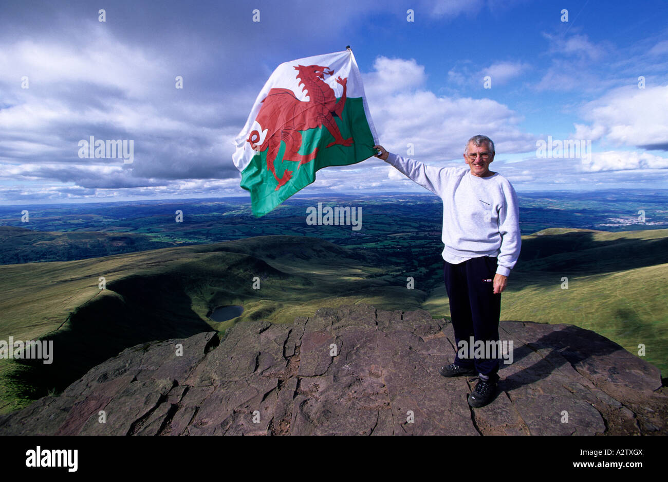 Man with Welsh flag on the summit of Pen-y-Fan, Brecon Beacons National Park, Powys, Wales Stock Photo