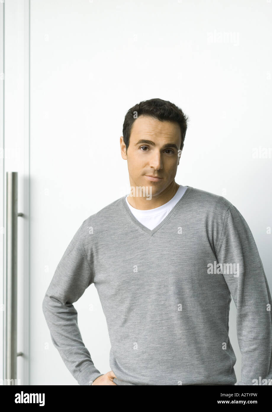 Man standing with hand on hip, looking at camera, portrait Stock Photo