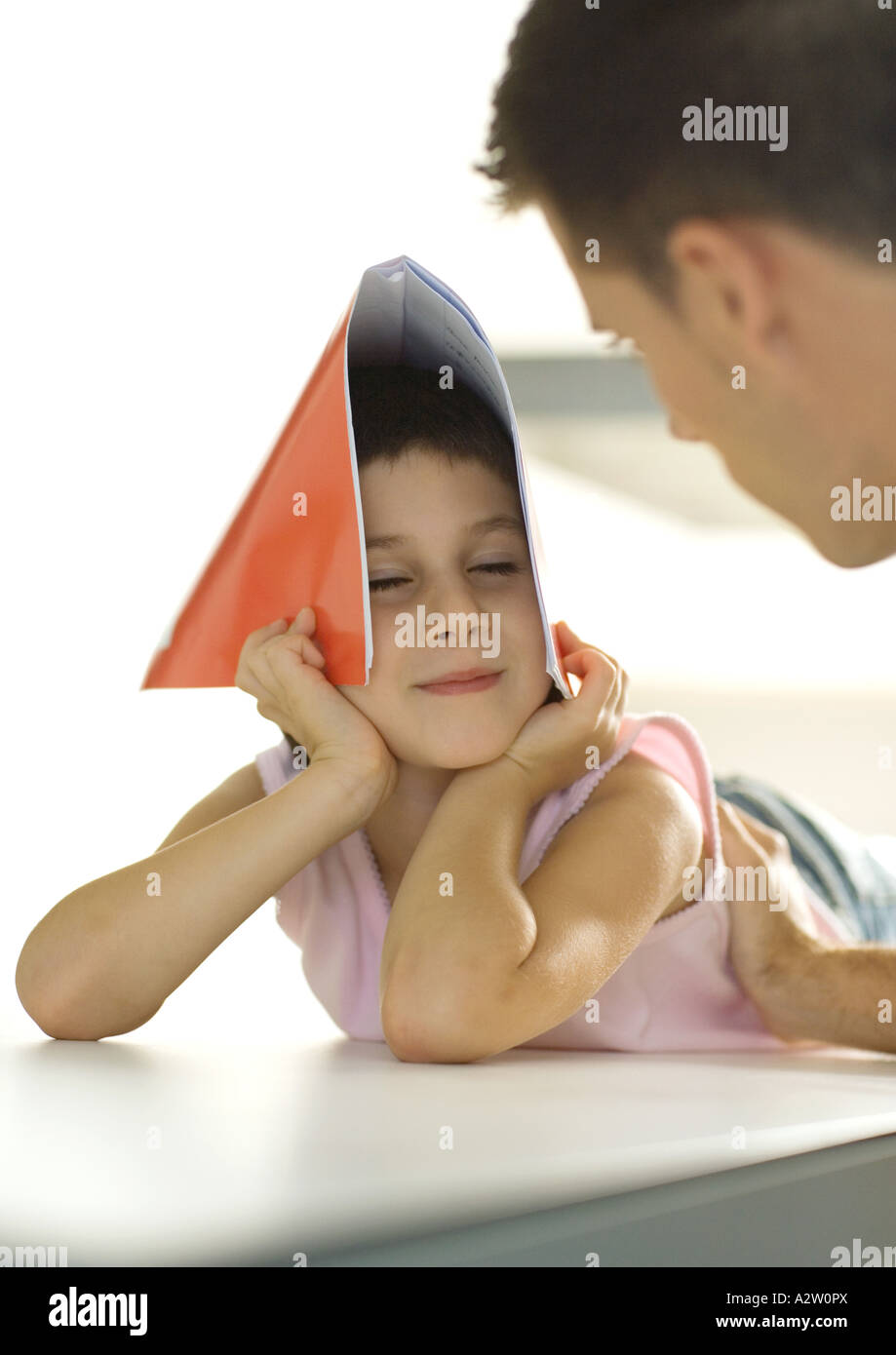 Girl holding notebook over head, turning toward father Stock Photo
