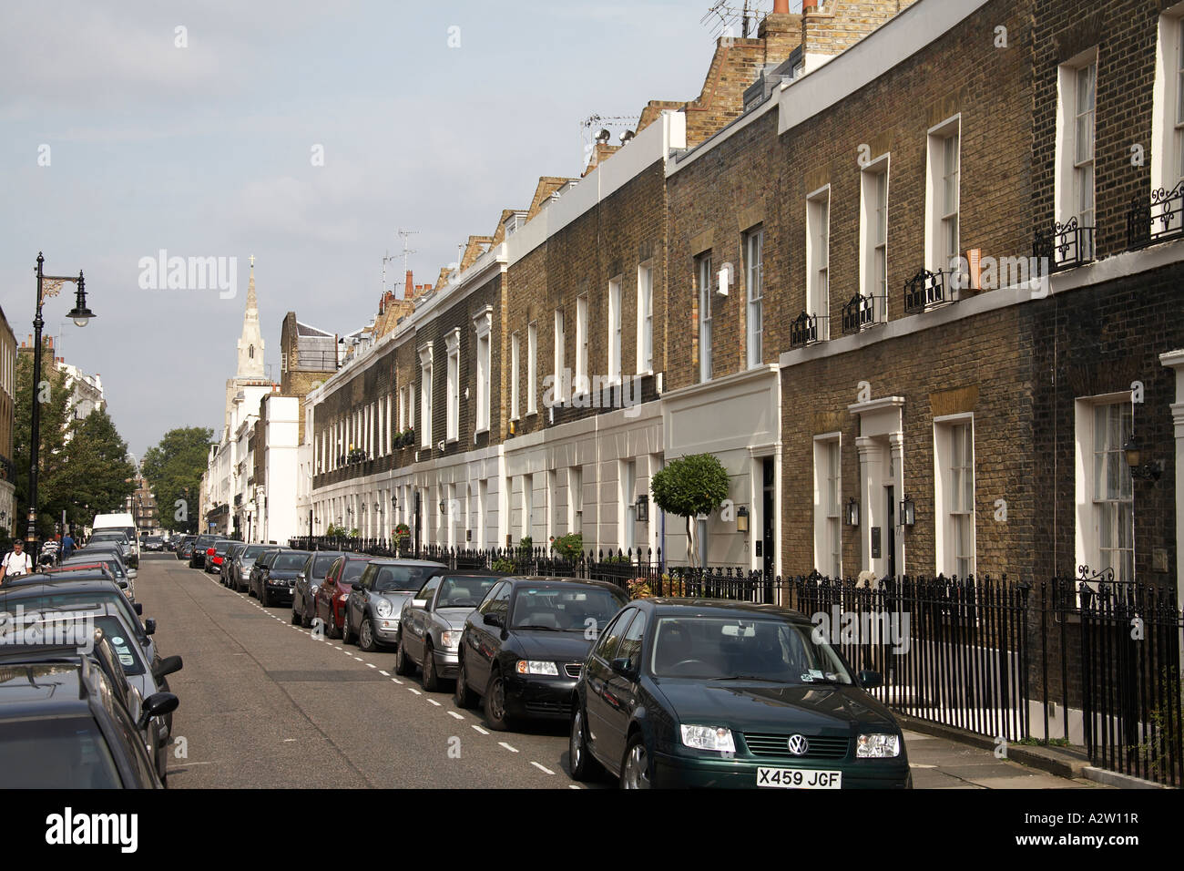 North east view along terraced Victorian houses of Chester Row street with cars and St Michael s Church in Belgravia London Stock Photo