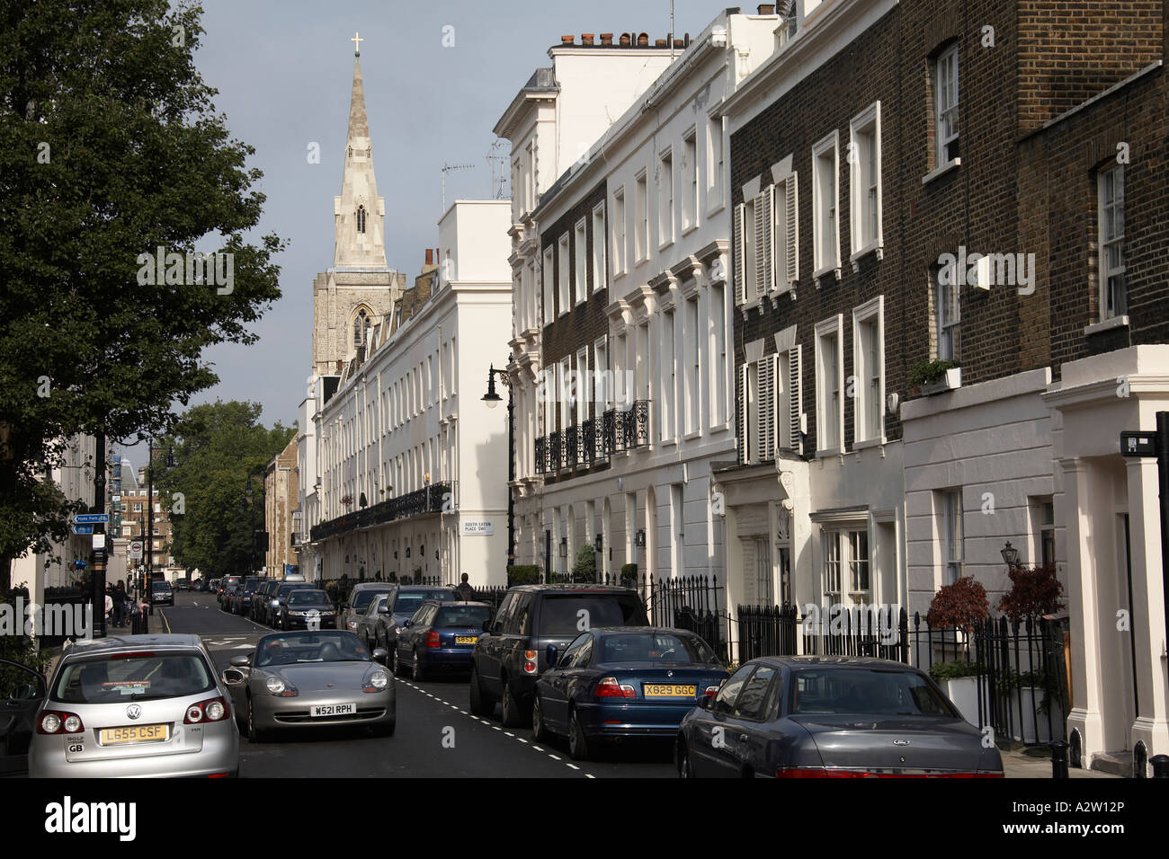 North east view along terraced Victorian houses of Chester Row street with cars and St Michael s Church in Belgravia London Stock Photo