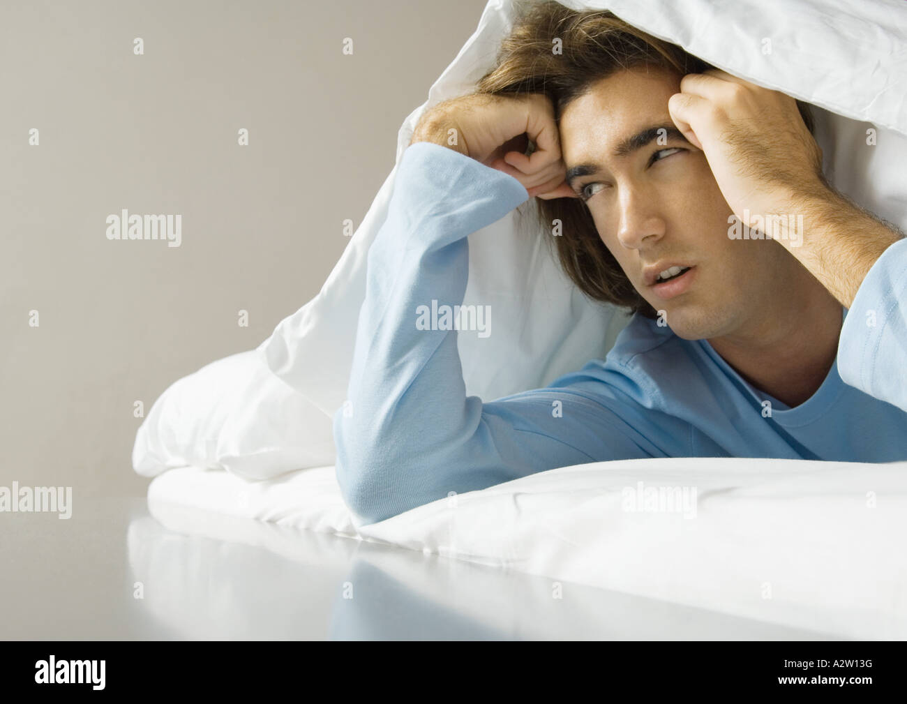 Man lying on stomach, under covers Stock Photo