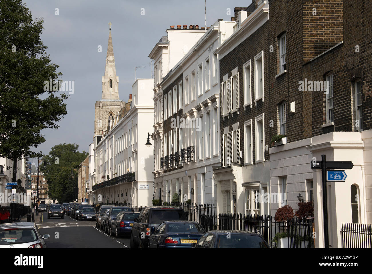 North east view along terraced Victorian houses of Chester Row street with cars and St Michael s Church in Belgravia London Stock Photo