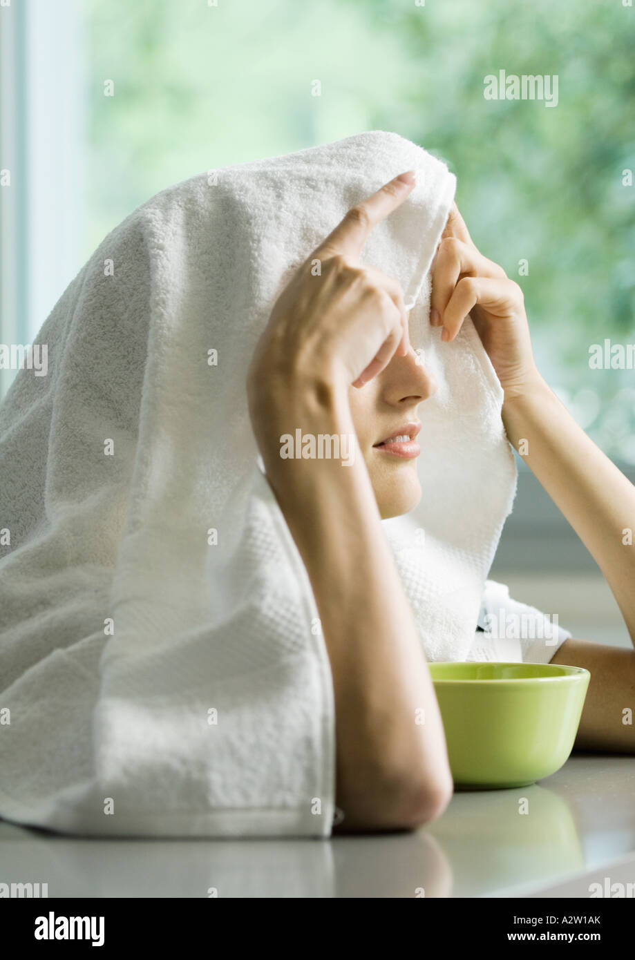 Woman with face over bowl and towel over head Stock Photo