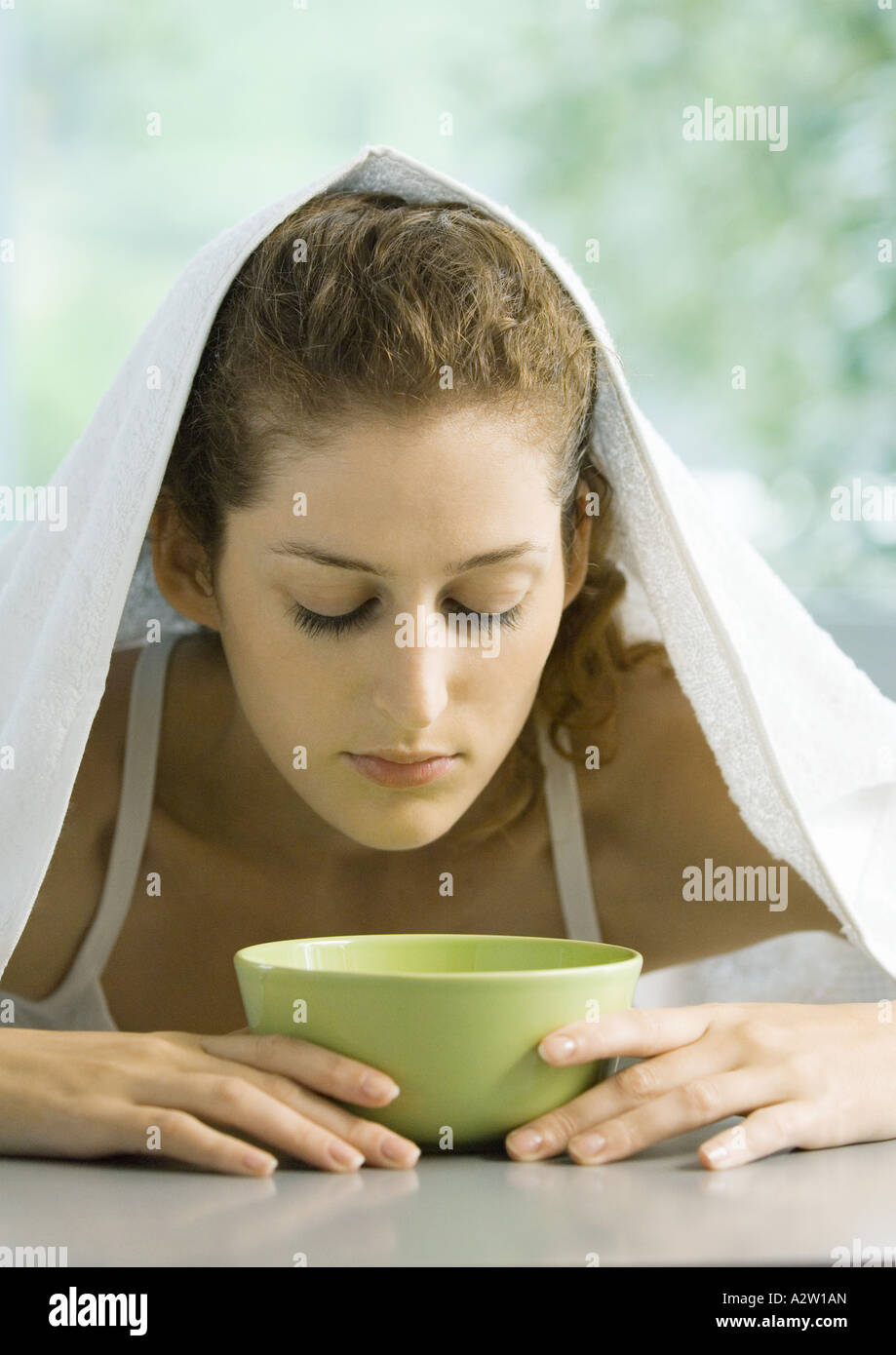 Woman with face over bowl and towel over head Stock Photo