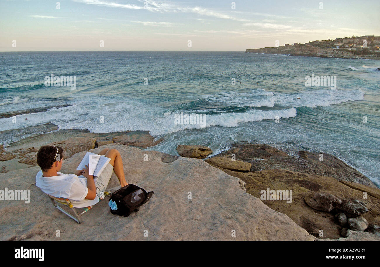 A man relaxing and reading a book on the famous cliffs of Sydney coastline, near Bondi beach, Australia. Stock Photo