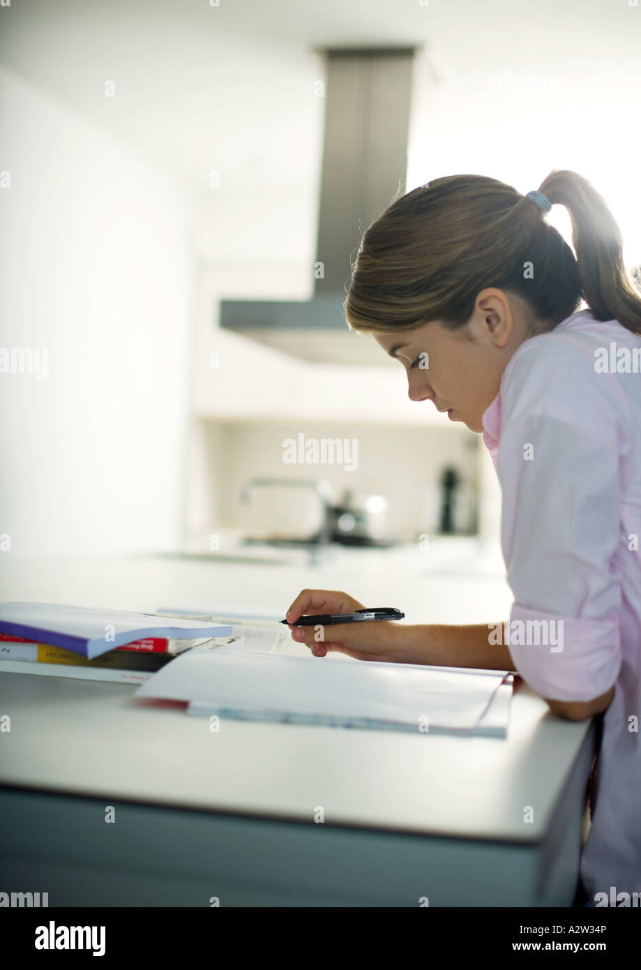 Teen girl doing homework in kitchen Stock Photo