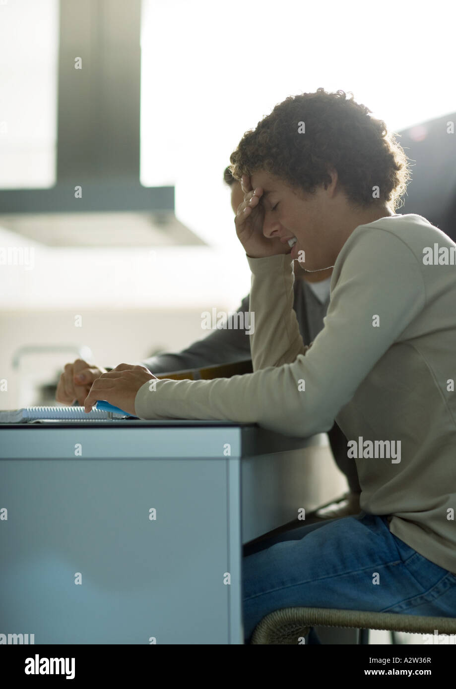 Man helping teenage son with homework, boy covering face Stock Photo