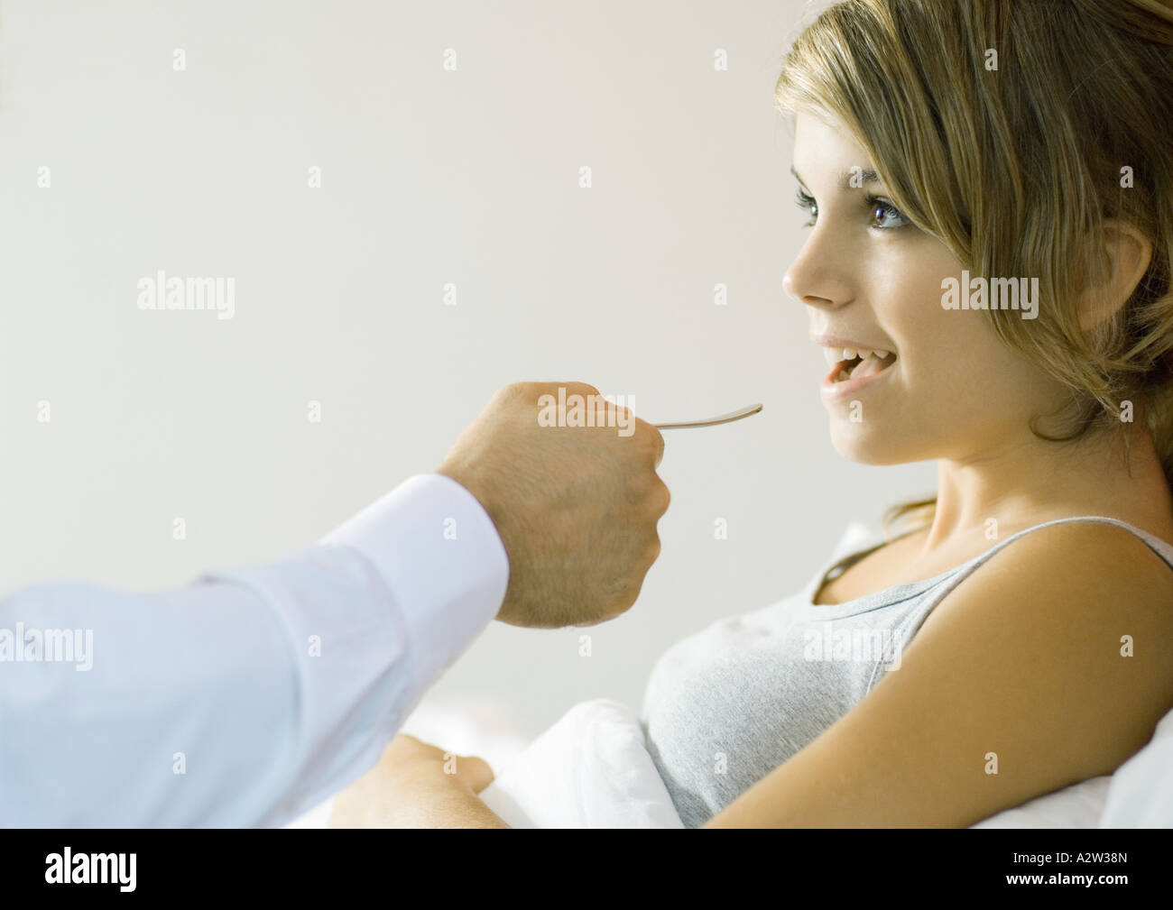 Young woman opening mouth for tongue depressor Stock Photo Alamy