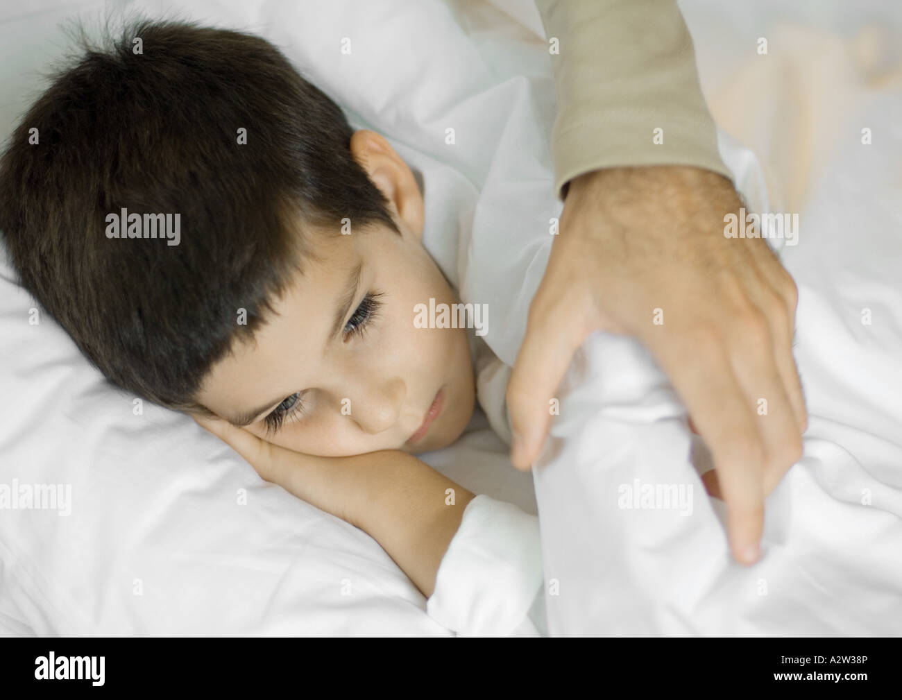 Man's hand putting blankets on child Stock Photo