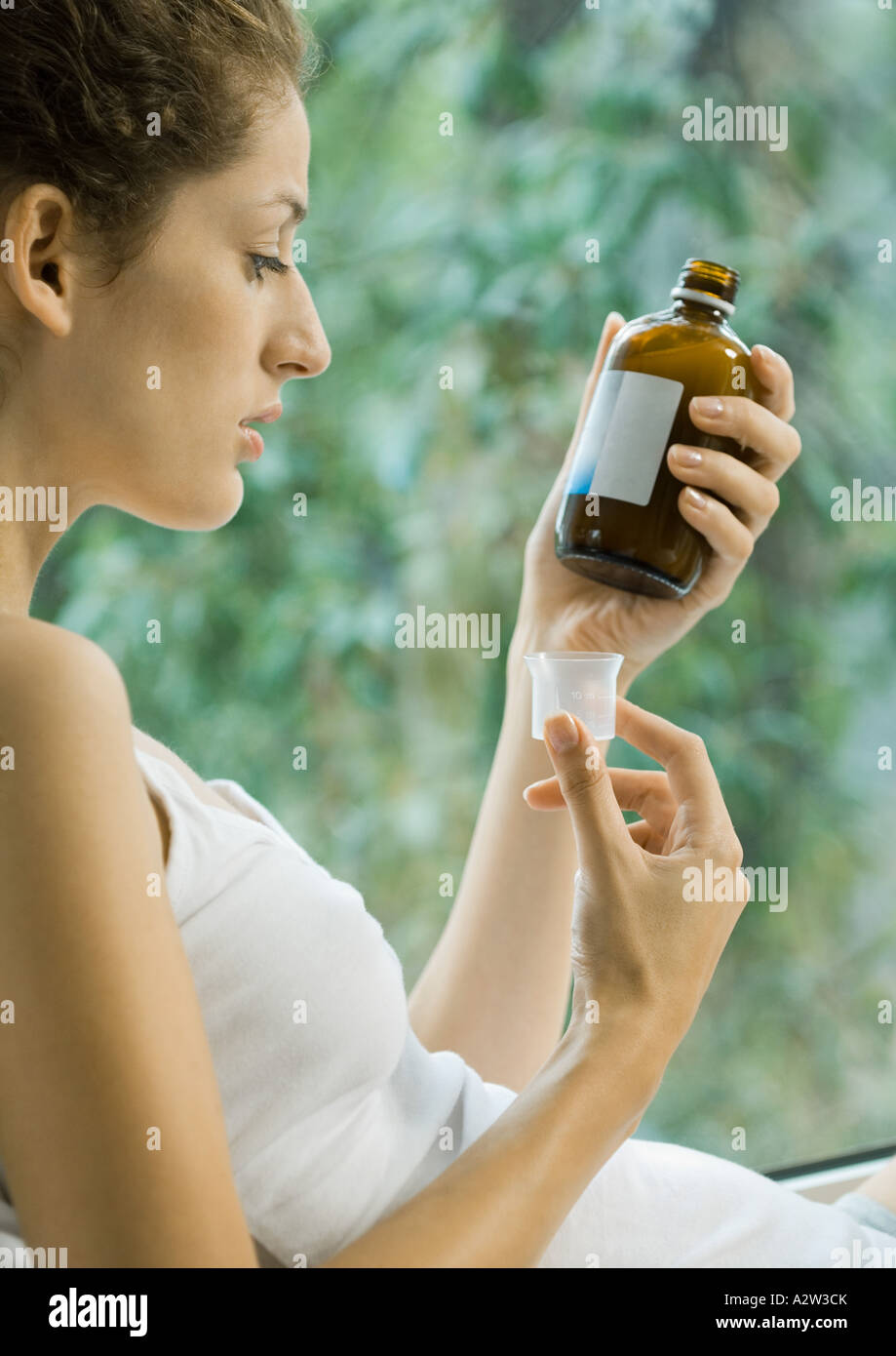 Woman looking at bottle of cough syrup Stock Photo Alamy