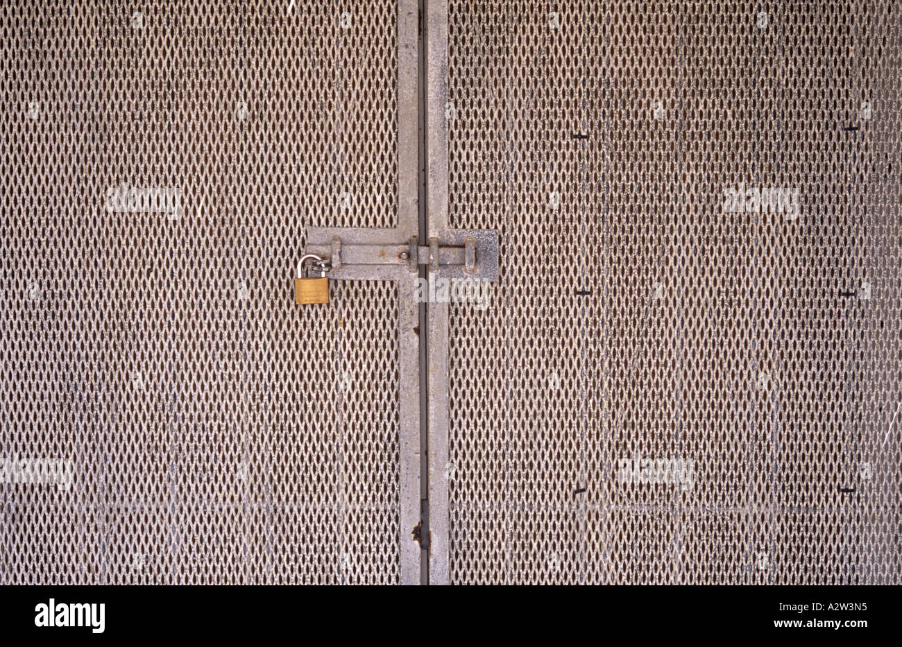 Detail of a pair of aluminium mesh security doors with sliding metal bar and padlock Stock Photo