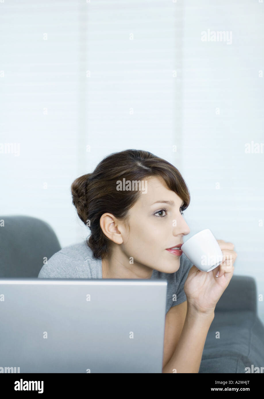 Woman using laptop and sipping coffee Stock Photo