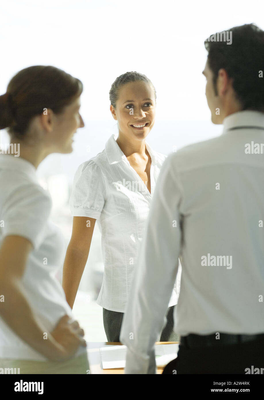 Three adults standing, talking in office Stock Photo - Alamy