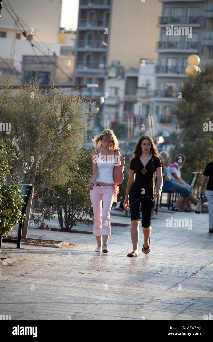 Two young girls or women walking in evening light on Sliema promenade Malta Stock Photo