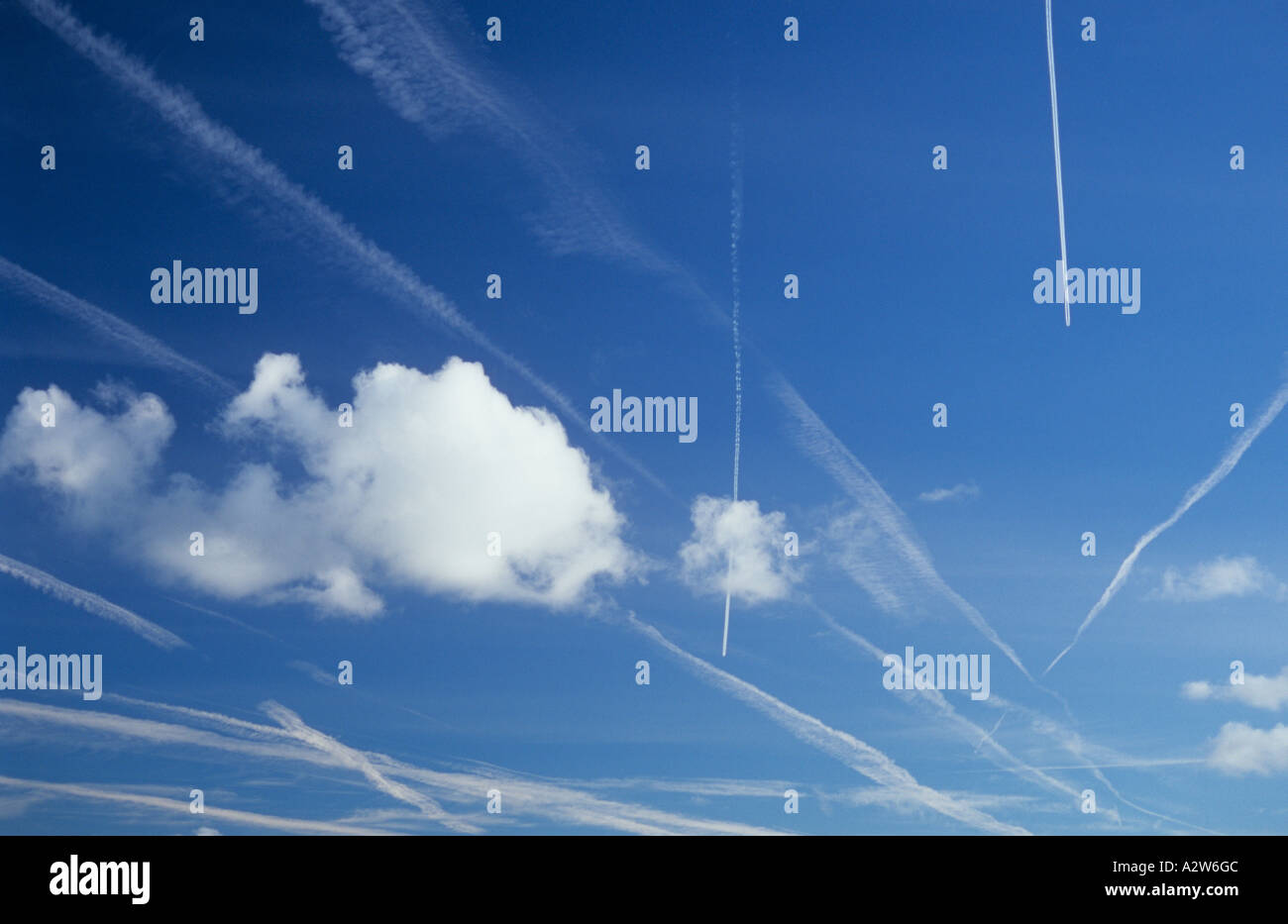Blue sky crowded with vapour trails or contrails recent and current and with small cumulus clouds Stock Photo
