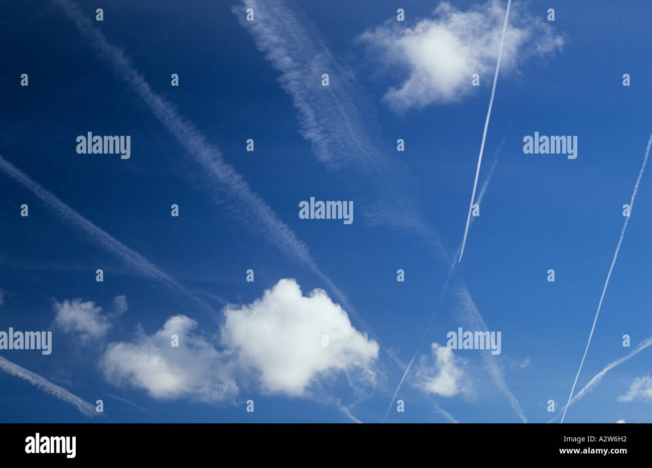 Blue sky crowded with vapour trails or contrails recent and current and with small cumulus clouds Stock Photo