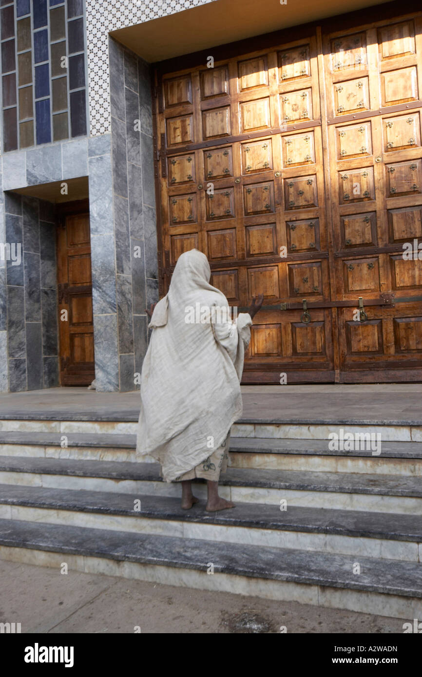Woman at steps in front of wooden door St Mary of Zion new church built by Haile Selassie in Aksum or Axum Ethiopia Africa Stock Photo
