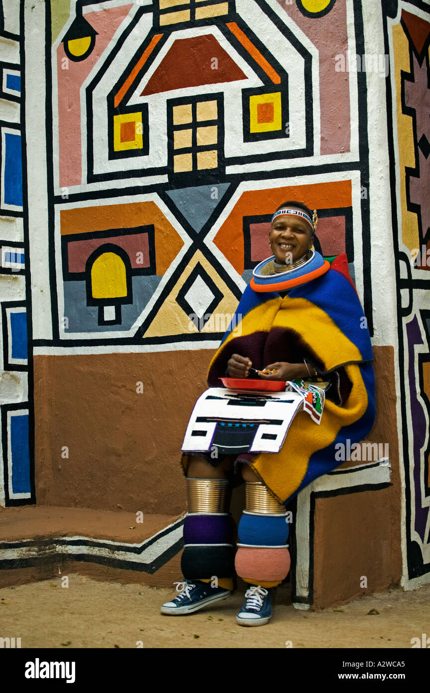 Ndebele woman dressed in traditional costume Married woman Traditional geometric wall paintings in background South Africa Stock Photo