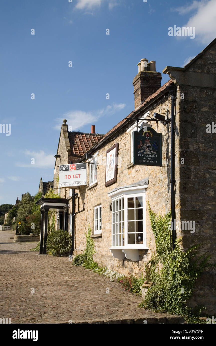 Ugly To Let sign on traditional sand stone pub in picturesque village Coxwold North Yorkshire England UK Britain Stock Photo