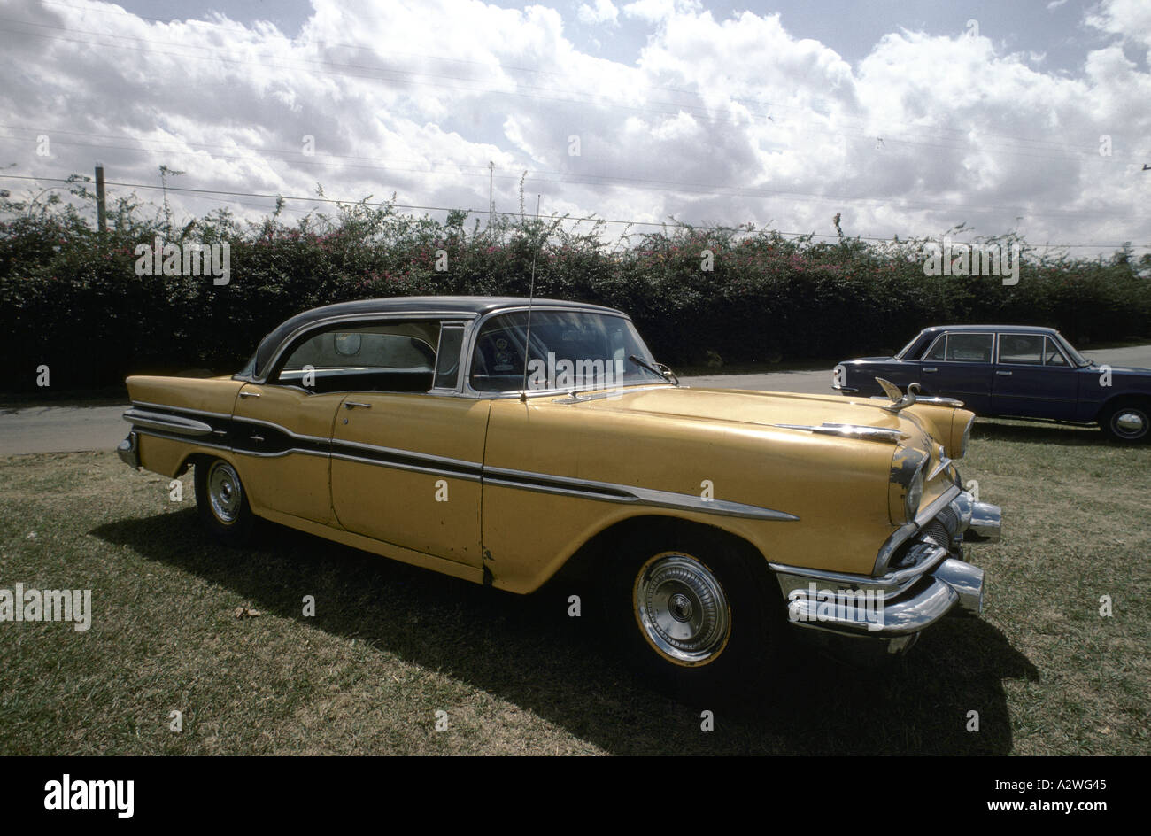 Classic yellow American car parked on the grass in Cuba Stock Photo