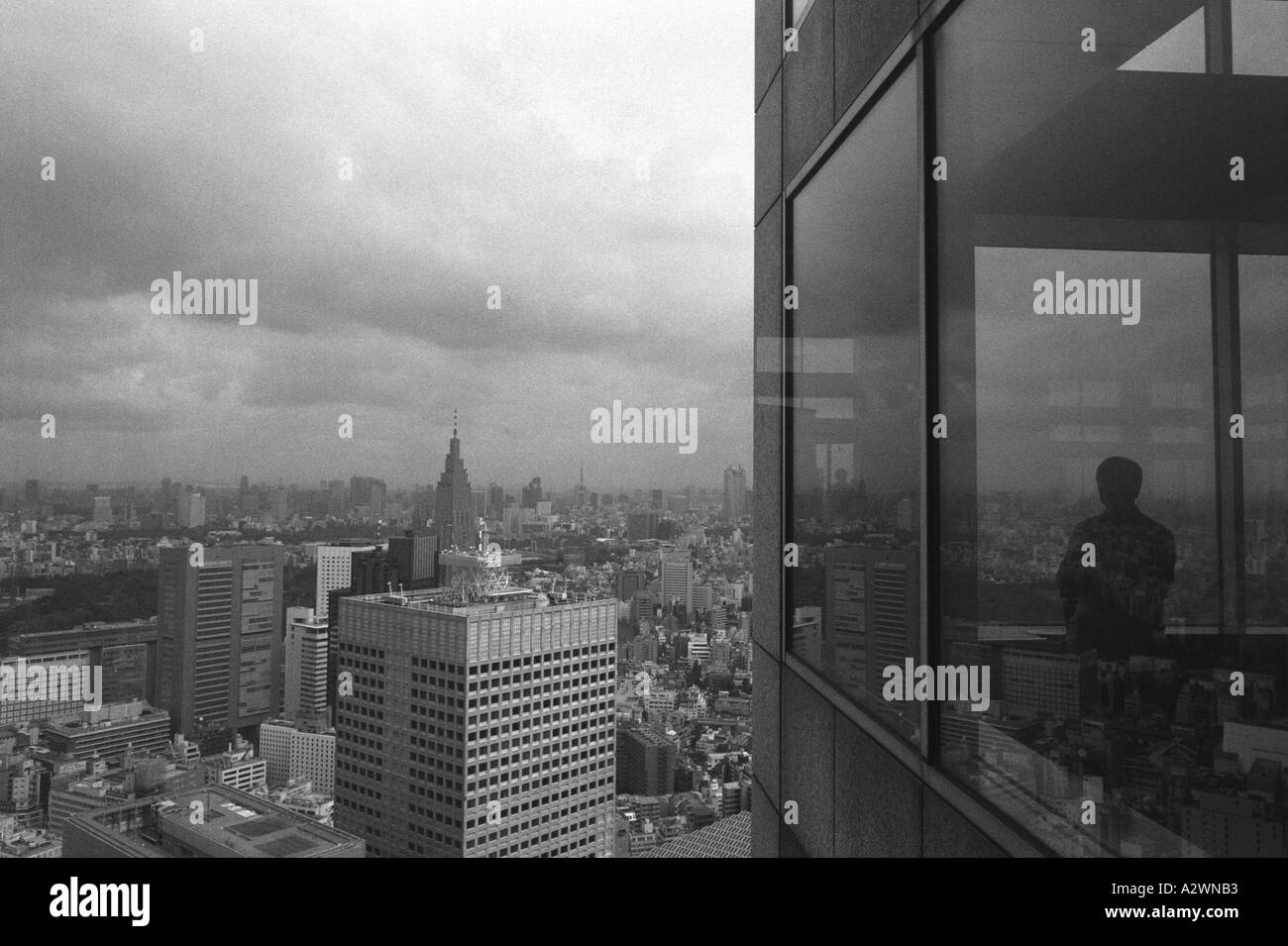 a man looks out over Shinjuku district of Tokyo from the viewing floor of the government building number 1. Stock Photo
