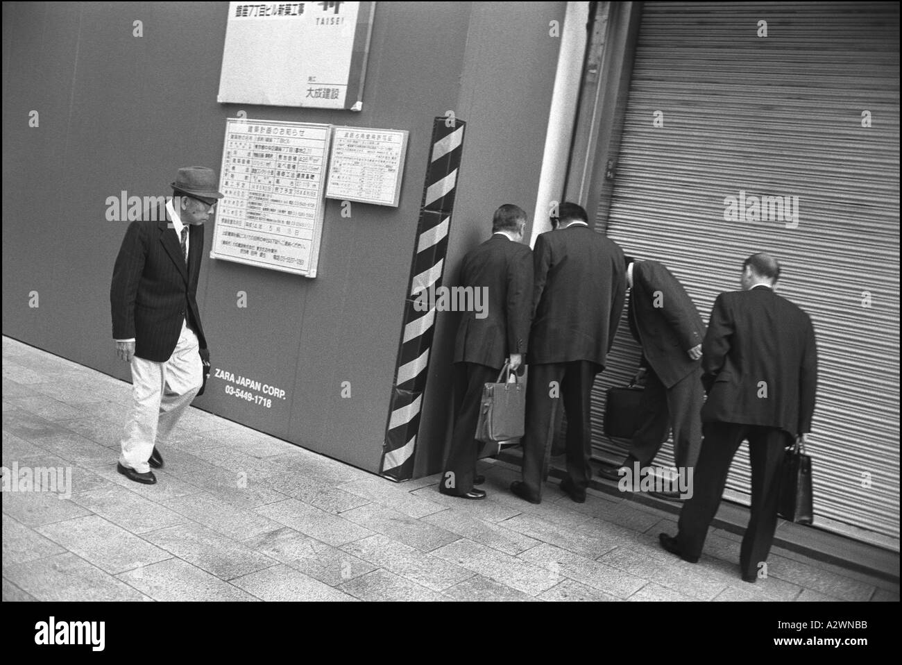 Men checking construction site wall, Ginza, Tokyo, Japan Stock Photo