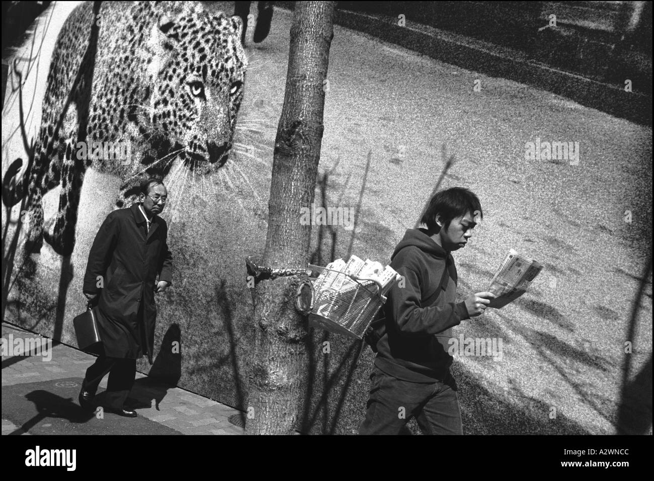 Japanese pedestrians pass a leopard on a billboard advertising Cartier jewellery, Ginza, Tokyo, Japan. Stock Photo