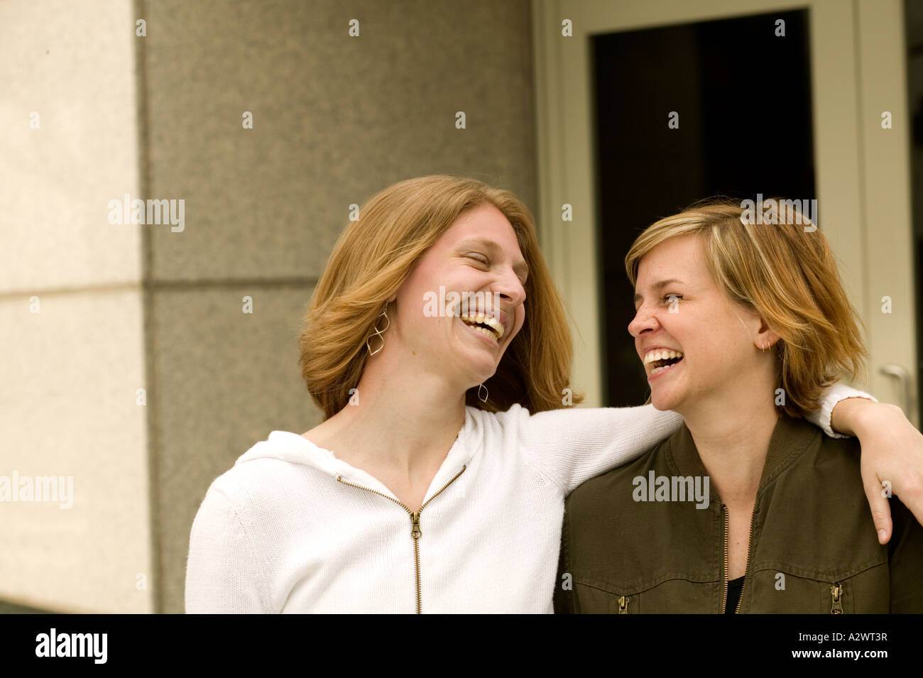 Young women smiling with arms around Stock Photo - Alamy