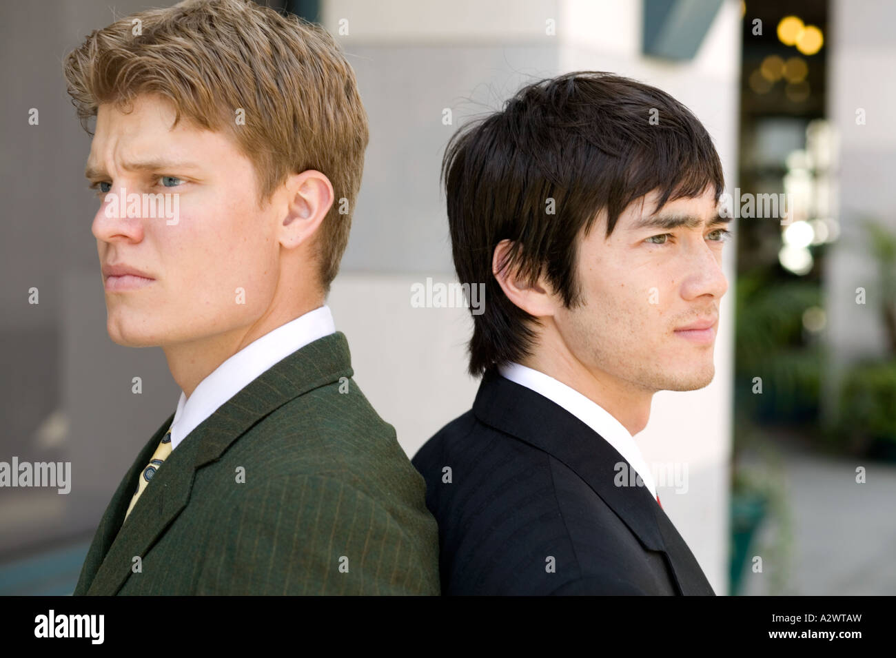 Young businessmen standing back to back Stock Photo - Alamy