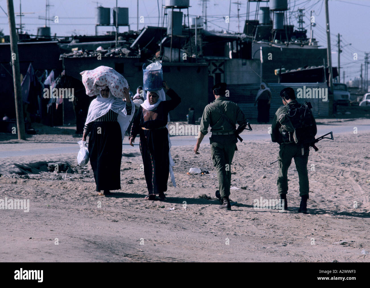 Women carrying their shopping on their heads and soldiers on the street, Gaza, Israeli Occupied Territories Stock Photo