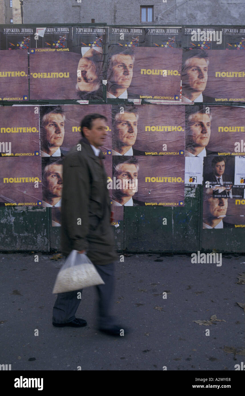 Belgrade under sanctions,  Dec 1993 : a man with bag of food walks past political posters before elections. Stock Photo