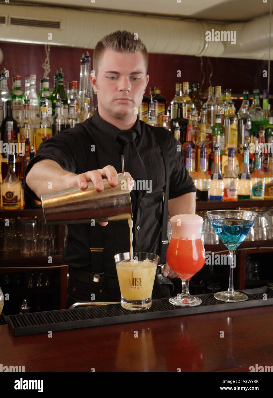 Barman pours a Whiskey Sour The Cocktails from the left Whiskey Sour Planters Punch Blue Lady Stock Photo